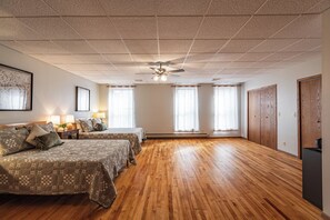 A hotel room with two beds, a ceiling fan, and large windows.