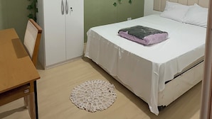 Una camera da letto con un letto, un armadio, un tavolo e una finestra.