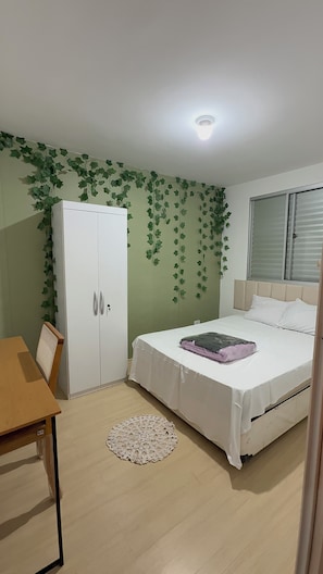 A bedroom with a bed, a wardrobe, a table, and a window. - Comfort & Convenience | 2-Bedroom Apartment - Wi-Fi and Parking (Cotia)