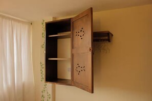 Ein Zimmer mit einem Holzschrank mit Klappe, einer kleinen Ablage und einem Haken zum Aufhängen.