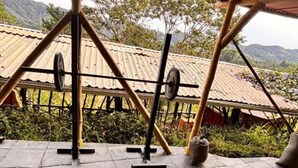 An outdoor gym area with exercise equipment, including a barbell, weight plates, and a blue exercise ball. - Ivy - with lake view (Guatapé)