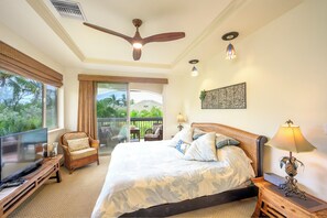 Ein Schlafzimmer mit einem Bett, einem Fernseher, einem Deckenventilator und Blick auf einen Balkon mit Gartenmöbeln.