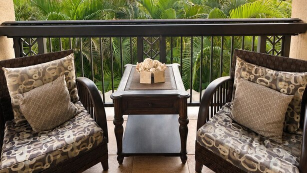 A balcony with two wicker chairs, a small table, and a decorative rug. - Mauna Lani Fairways Resort Townhouse w/ Beach Club (Waimea)