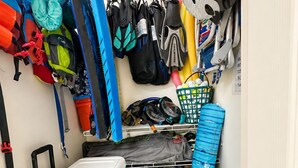 A storage area with a blue cooler, various bags, helmets, and a rack with items. - Mauna Lani Fairways Resort Townhouse w/ Beach Club (Waimea)