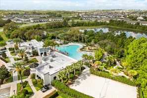 Una zona residencial con piscina, rodeada de vegetación y un lago pequeño.