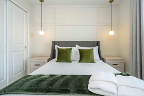 A neatly made bed with a green throw blanket, two bedside tables with lamps, and a white door. - Luxury Escape 5 BD/ 5.5 BA/ Windsor Cay - 16105 PF (Clermont)