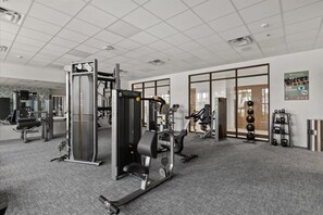 A gym with various exercise machines, a kettlebell rack, and a poster on the wall. - Luxury Escape 5 BD/ 5.5 BA/ Windsor Cay - 16105 PF (Clermont)