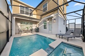 Ein Swimmingpool mit Liegestühlen und einem Tisch, umgeben von einer überdachten Terrasse.
