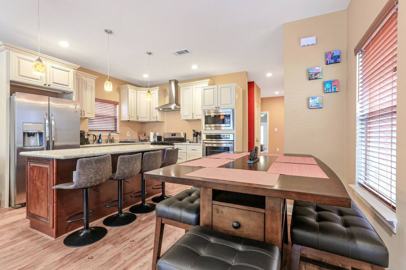 Una cocina moderna con una isla central, taburetes de bar y una mesa de comedor.