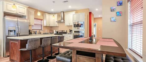 Una cocina moderna con una isla central, taburetes de bar y una mesa de comedor.