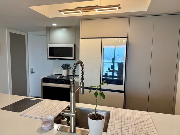 A modern kitchen with a stainless steel sink, a microwave, and a potted plant. - Luxury 2-bedroom apartment with amenities in Downtown Miami, featuring ocean and park views (Miami)