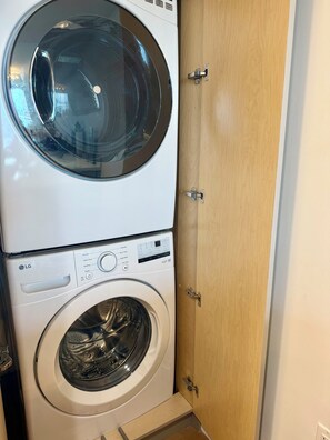 A stacked washer and dryer unit with a control panel and a wooden door. - Luxury 2-bedroom apartment with amenities in Downtown Miami, featuring ocean and park views (Miami)