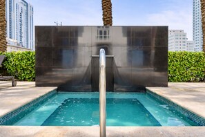 A swimming pool with a modern design, surrounded by a stone wall and palm trees. - Luxury 2-bedroom apartment with amenities in Downtown Miami, featuring ocean and park views (Miami)