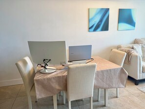 A dining area with a table, chairs, and two laptops. There are two abstract paintings on the wall. - Luxury 2-bedroom apartment with amenities in Downtown Miami, featuring ocean and park views (Miami)