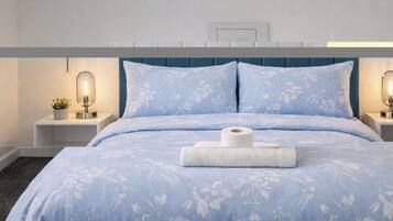 Ein ordentlich gemachtes Bett mit Blumenmuster, zwei Nachttische mit Lampen und einer Wandleuchte.