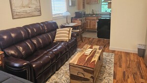 Uma sala de estar com um sofá de couro, uma mesa de centro e um quadro na parede.