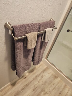 A bathroom with a wooden floor, a towel rack with two towels, and a glass shower door. - Delightful NEW listing, freshly remodeled,Bayfield perfect for relax & adventure (Bayfield)
