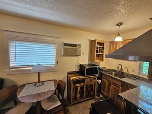 A compact kitchen with a microwave, stove, sink, and wooden cabinets.