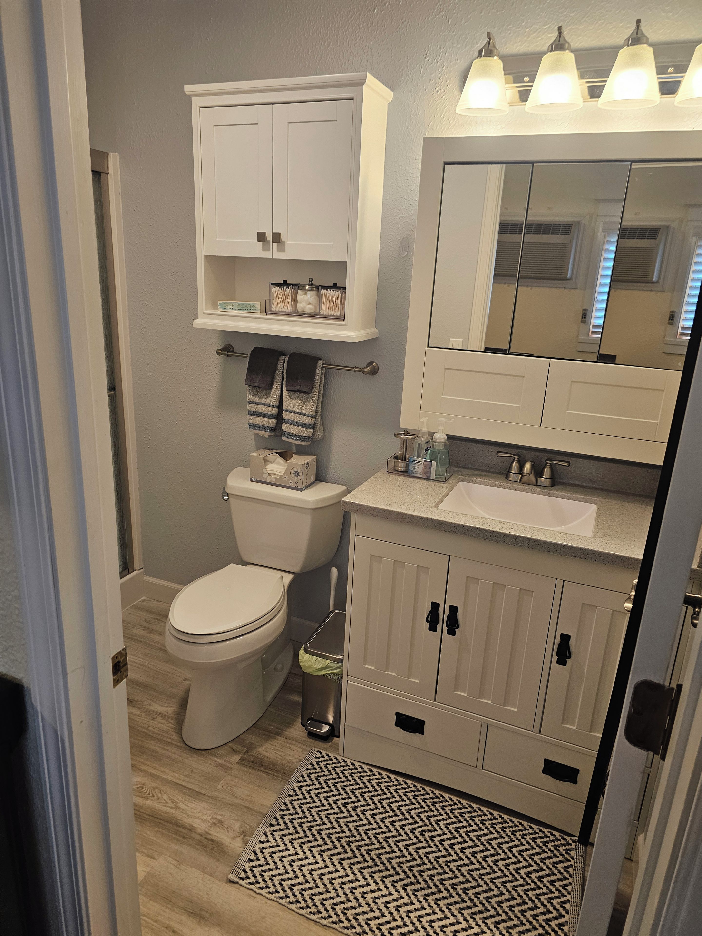 A bathroom with a toilet, sink, and cabinet.