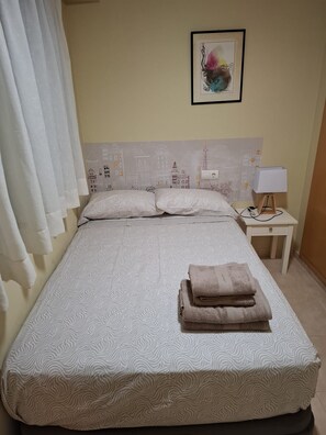 Ein Hotelzimmer mit Bett, Kissen, einem Nachttisch mit Lampe und einem Bild an der Wand.