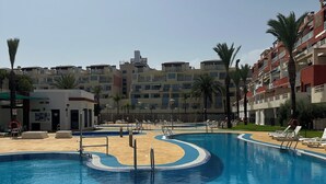 Ein Pool mit geschwungener Kante, umgeben von Liegestühlen und Palmen.