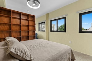 Una camera da letto con un letto, un armadio in legno e due finestre.