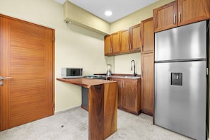 A kitchen with wooden cabinets, a stainless steel refrigerator, a microwave, and a stove. - The Malecon Loft 1 Min to Beach & Boardwalk (Puerto Vallarta)