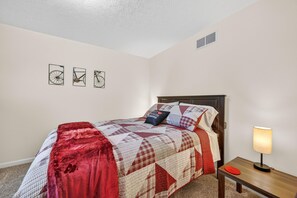 A bedroom with a bed, a nightstand, a lamp, and three wall art pieces. - Hoosier House on S. Park Ave. Newly renovated, Close to IU Campus, (Bloomington)