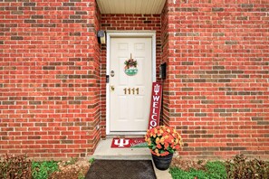 A brick building with a white door, a welcome sign, and a potted plant with flowers. - Hoosier House on S. Park Ave. Newly renovated, Close to IU Campus, (Bloomington)