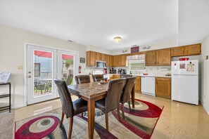 A modern kitchen with wooden cabinets, a dining table with chairs, and a refrigerator. - Hoosier House on S. Park Ave. Newly renovated, Close to IU Campus, (Bloomington)