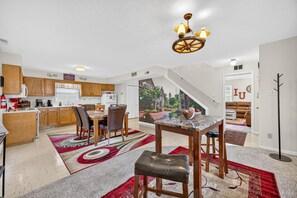 A spacious kitchen with wooden cabinets, a dining area with a marble table, and a staircase leading to a living area. - Hoosier House on S. Park Ave. Newly renovated, Close to IU Campus, (Bloomington)