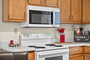 A kitchen with wooden cabinets, a white stove, a microwave, and a coffee station. - Hoosier House on S. Park Ave. Newly renovated, Close to IU Campus, (Bloomington)