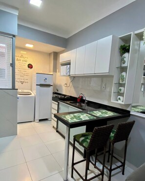 A compact kitchen with a central island, white cabinetry, and a small refrigerator.