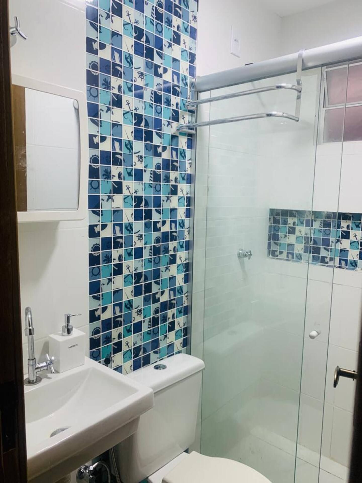 Un baño con cabina de ducha azulejada, un lavamanos y un inodoro.