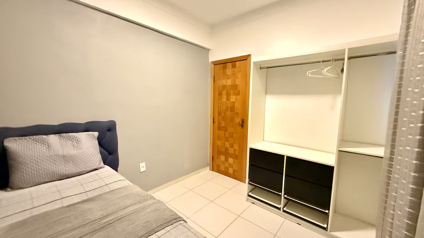 A bedroom with a bed, a wardrobe, and a closet with shelves.