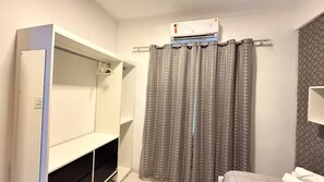 A bathroom with a shower curtain, a towel rack, and a wall-mounted air conditioning unit.
