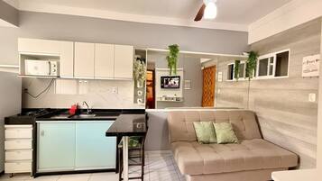 A modern kitchen with a dining area, a sofa, and a ceiling fan.
