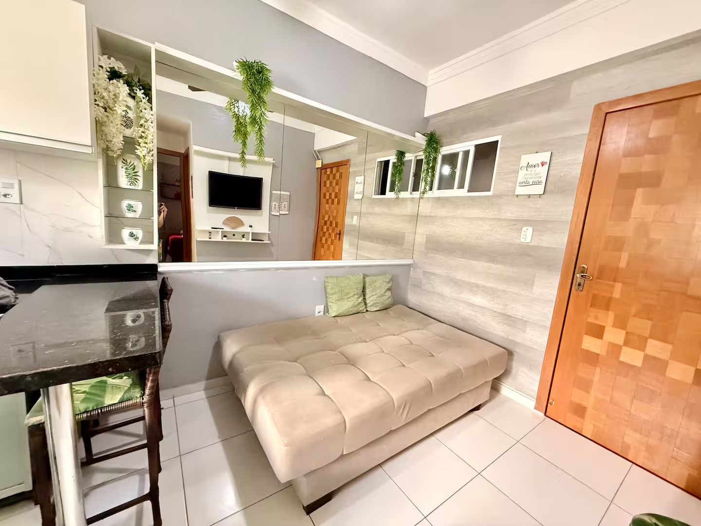 Ein modernes Wohnzimmer mit einer Couch, einem an der Wand montierten Fernseher und einer Holztür.