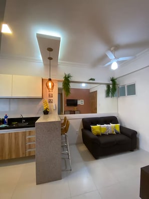 A modern living space with a kitchen, dining area, and a black sofa with yellow cushions. - 204 - Cozy 2-bedroom apartment (Belém)