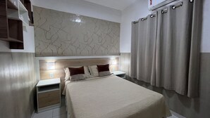 Een slaapkamer met een bed, nachtkastjes, een wandplank en gordijnen.