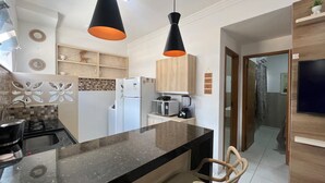 Een moderne keuken met een centraal eiland, hanglampen en een magnetron.