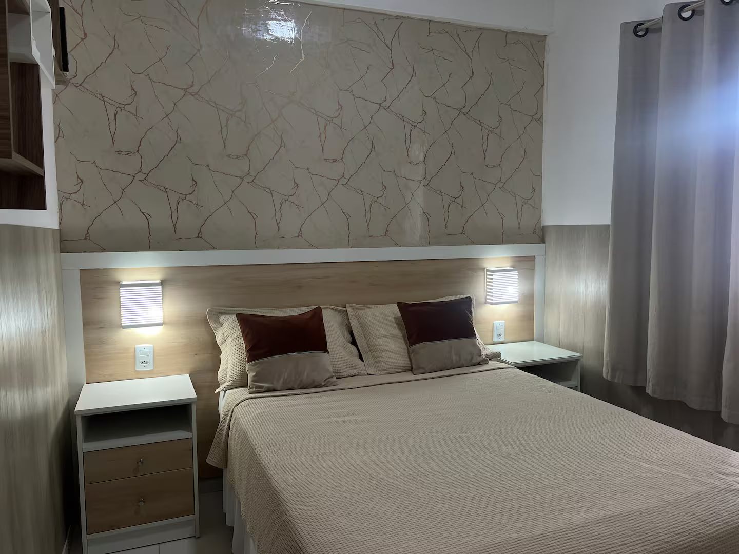 Ein Schlafzimmer mit einem Bett, Nachttischen und einer Wand mit Marmoroptik.