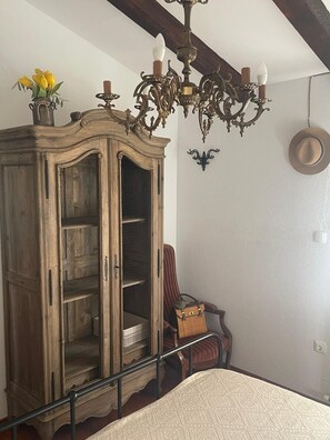 Ein Zimmer mit Holzschrank, Bett, Stuhl und einer Chandelier.