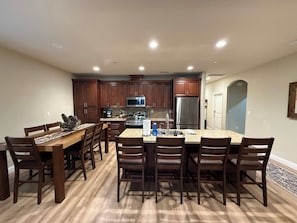 A modern kitchen with dark wooden cabinets, stainless steel appliances, and a central island with seating. - Silver Pines Modern Retreat-3BR New Build (Shaver Lake)