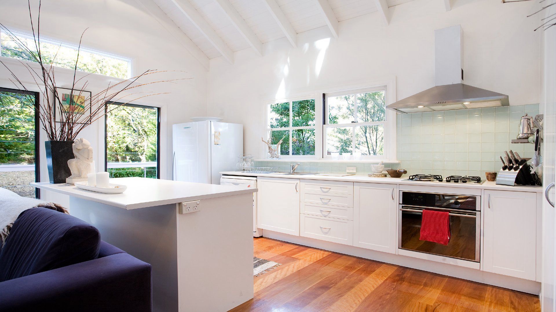 A modern kitchen with white cabinetry, a built-in oven, and a stainless steel range hood.
