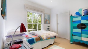 A bedroom with a bed, a desk, a window, and a wardrobe.