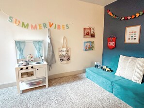 A child's room with a white dresser, a blue sofa, and a wall with various decorations including a 'SUMMER VIBES' banner. - Spacious 4-bedroom house in peaceful neighborhood. (Jerome)