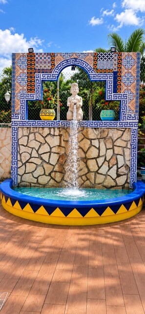 A fountain with a statue, surrounded by a decorative tiled wall with geometric patterns.