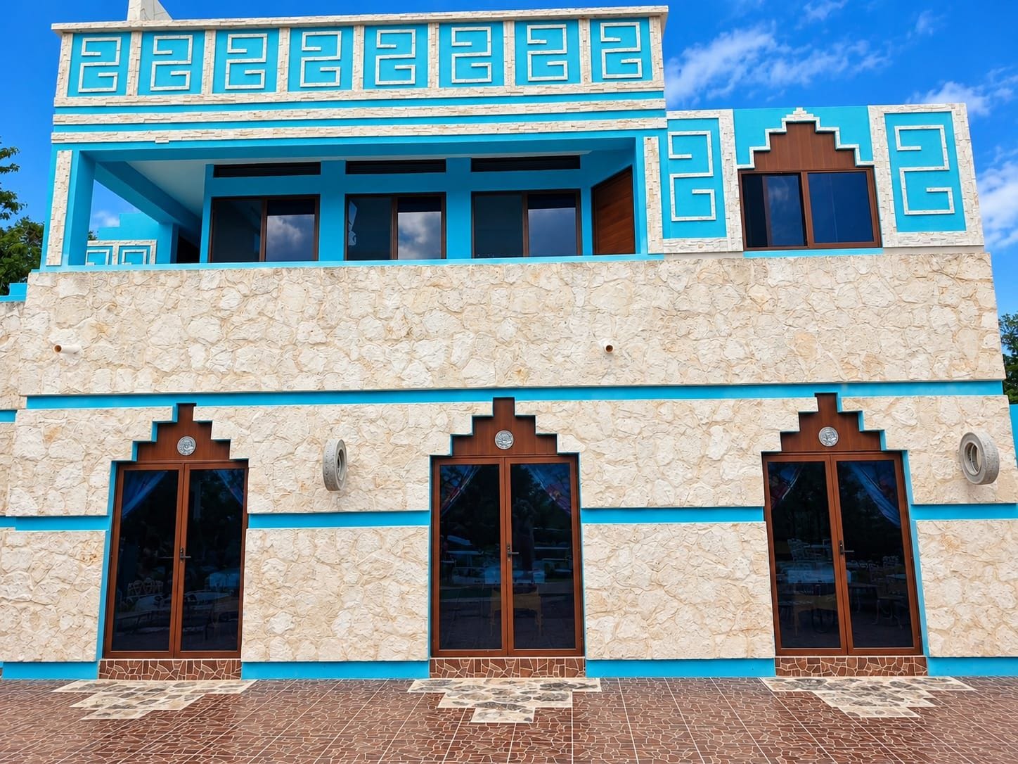 Un edificio de dos pisos con fachada de piedra y detalles en azul.