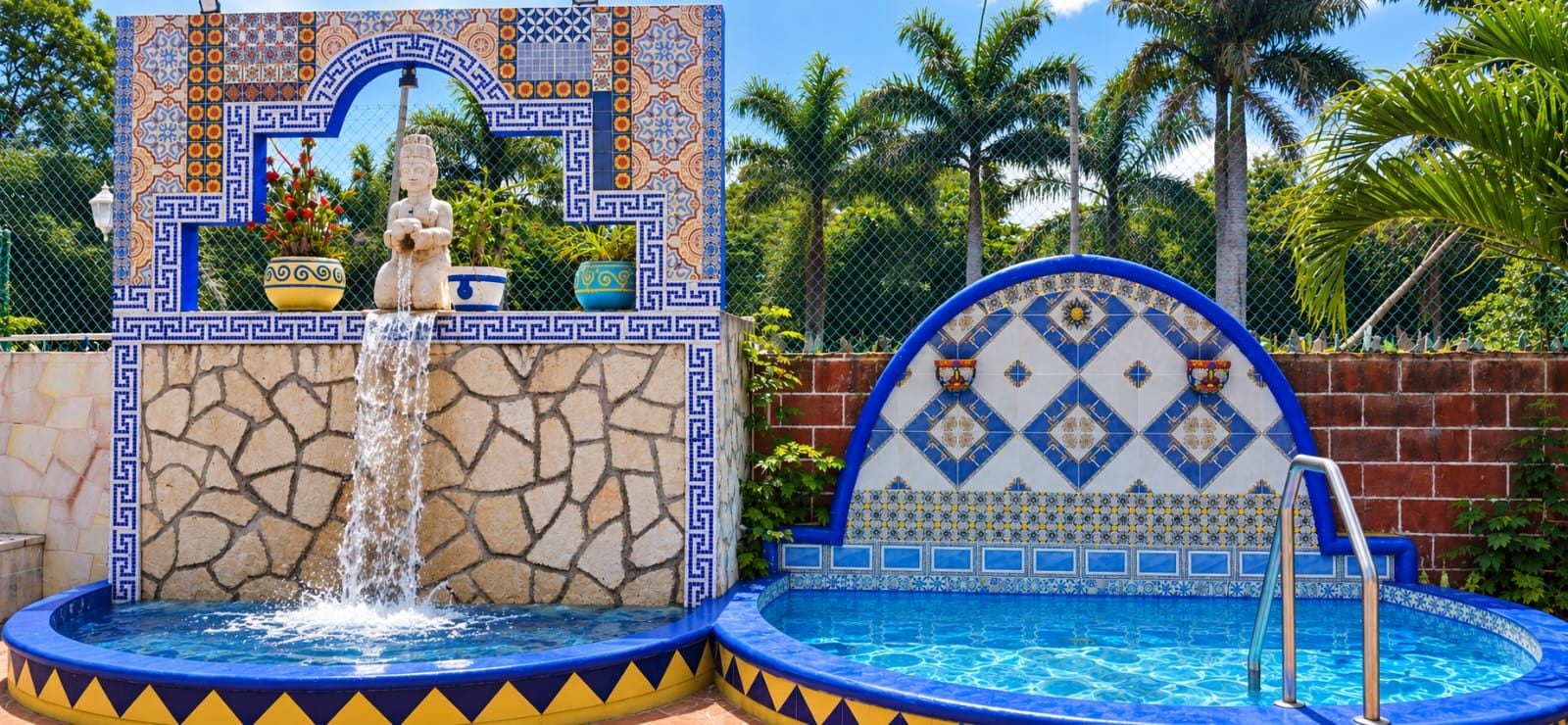 A pool area with a fountain, tiled walls, and a statue.
